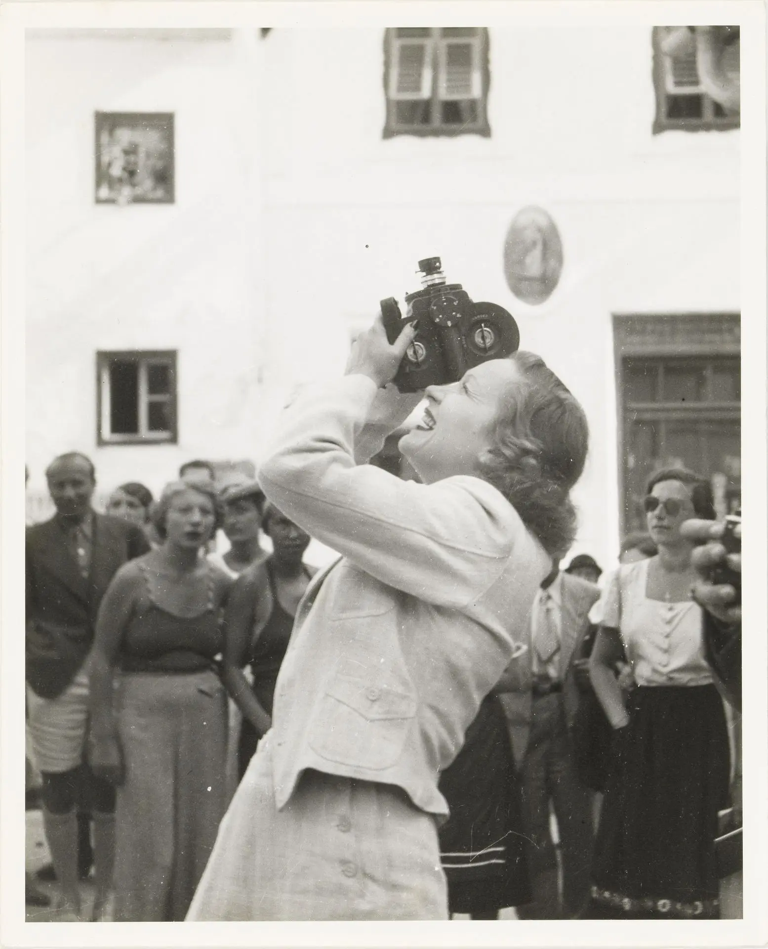 Robert Haas: Marlene Dietrich bei den Salzburger Festspielen, 11.8.1936, Foto: Birgit und Peter Kainz, Wien Museum Im Vordergrund ist Marlene Dietrich zu sehen die ihre Kamera nach oben richtet, im Hintergrund eine Menschenmenge